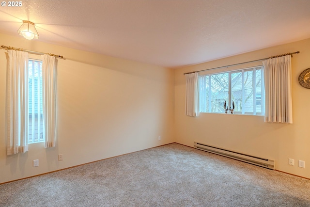 carpeted spare room featuring a baseboard heating unit and a healthy amount of sunlight