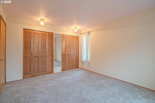 unfurnished bedroom with baseboards, multiple closets, and carpet floors