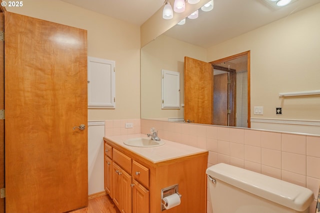 full bath with toilet, vanity, decorative backsplash, a shower with shower door, and tile walls