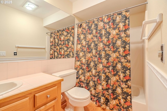 bathroom featuring a wainscoted wall, toilet, a shower with shower curtain, tile walls, and vanity