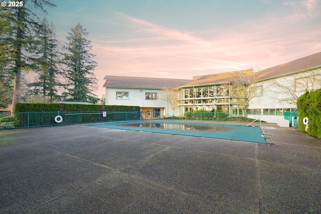 pool at dusk with a community pool, a patio, and fence