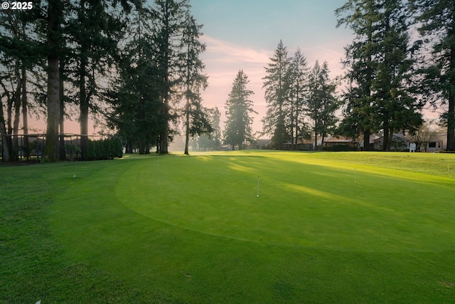 view of home's community with view of golf course and a lawn