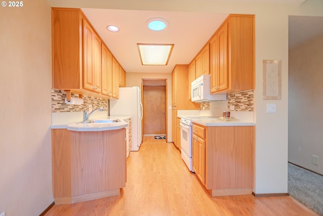 kitchen with a sink, white appliances, light wood-style floors, and light countertops