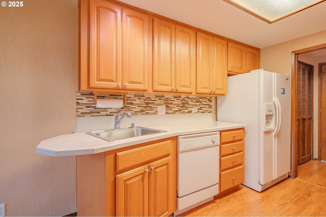 kitchen featuring a sink, white appliances, backsplash, and light wood-style flooring