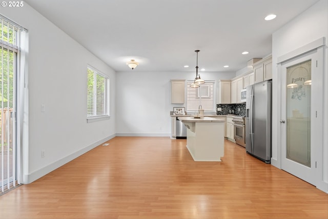 4345 SW Vino Pl, Beaverton, OR 97078 - kitchen featuring appliances with stainless steel finishes, light wood finished floors, backsplash, a kitchen island, and recessed lighting