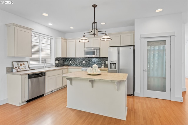 4345 SW Vino Pl, Beaverton, OR 97078 - kitchen featuring appliances with stainless steel finishes, a sink, light countertops, light wood-style flooring, and recessed lighting