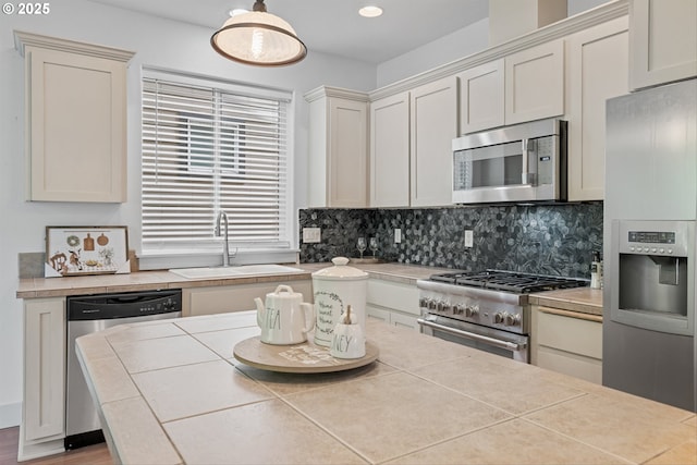 4345 SW Vino Pl, Beaverton, OR 97078 - kitchen featuring appliances with stainless steel finishes, a sink, backsplash, tile counters, and wood finished floors