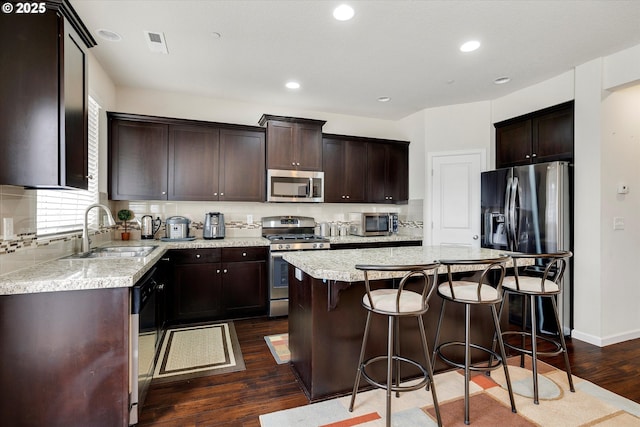 kitchen with a kitchen island, appliances with stainless steel finishes, dark hardwood / wood-style floors, sink, and decorative backsplash