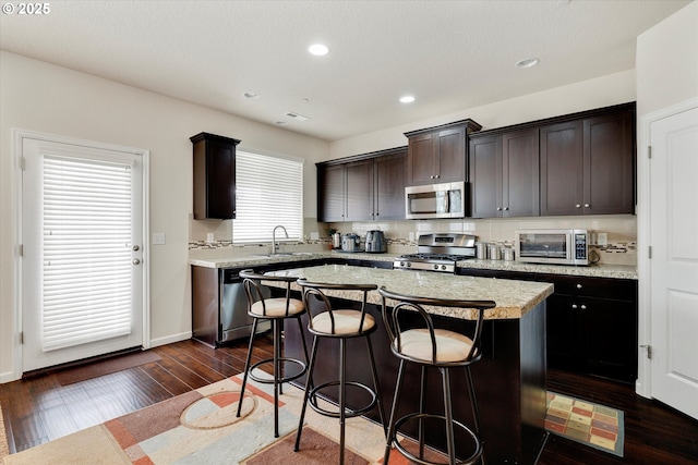 kitchen featuring sink, stainless steel appliances, dark hardwood / wood-style floors, dark brown cabinetry, and a kitchen island