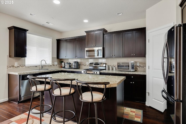 kitchen featuring sink, tasteful backsplash, appliances with stainless steel finishes, dark hardwood / wood-style flooring, and a kitchen island