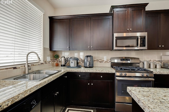 kitchen with tasteful backsplash, sink, dark brown cabinets, and appliances with stainless steel finishes