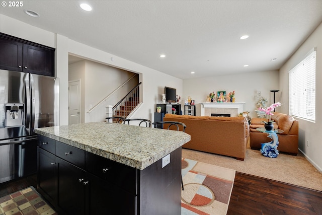 kitchen with a tile fireplace, stainless steel refrigerator with ice dispenser, a center island, and light wood-type flooring