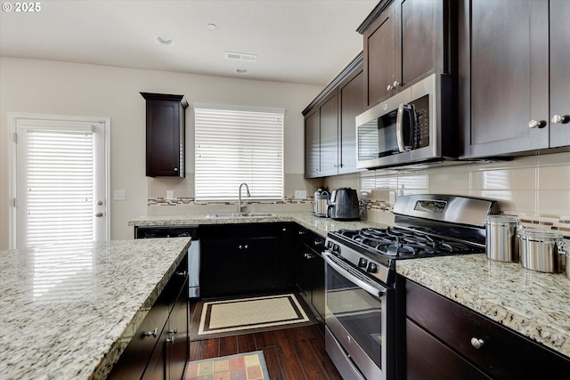 kitchen featuring tasteful backsplash, dark hardwood / wood-style flooring, dark brown cabinetry, light stone counters, and stainless steel appliances