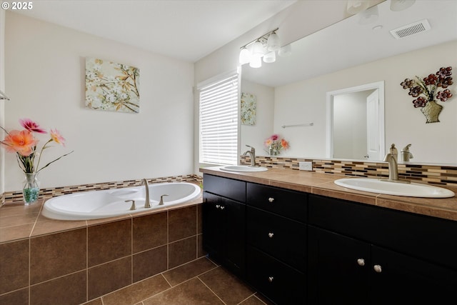 bathroom featuring vanity, decorative backsplash, tile patterned floors, and a relaxing tiled tub