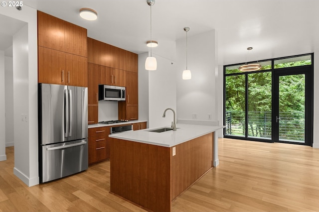 922 NW 11th Ave Unit 209, Portland, OR 97209 - kitchen with appliances with stainless steel finishes, light wood-type flooring, brown cabinetry, light countertops, and a wall of windows