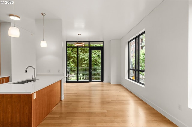 922 NW 11th Ave Unit 209, Portland, OR 97209 - kitchen featuring brown cabinets, light wood-style flooring, light countertops, and pendant lighting