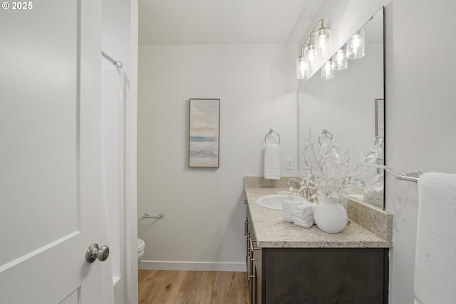 bathroom with vanity, wood finished floors, toilet, and baseboards