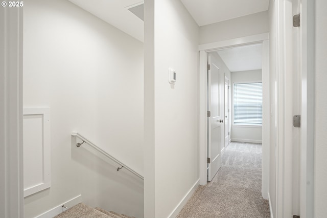 corridor featuring baseboards, visible vents, an upstairs landing, and light colored carpet