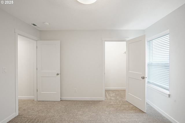 unfurnished bedroom featuring light carpet and baseboards