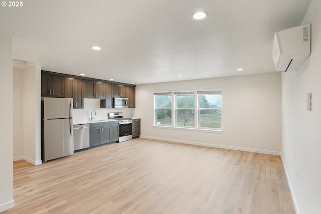 kitchen with a wall unit AC, recessed lighting, stainless steel appliances, a sink, and light countertops