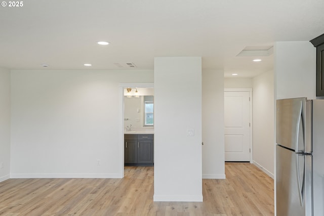 empty room featuring baseboards, light wood-style flooring, visible vents, and a sink