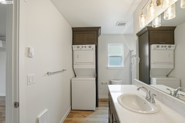 bathroom featuring visible vents, stacked washer and dryer, and toilet