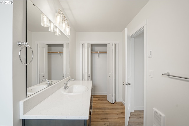 bathroom featuring visible vents, a walk in closet, wood finished floors, and vanity