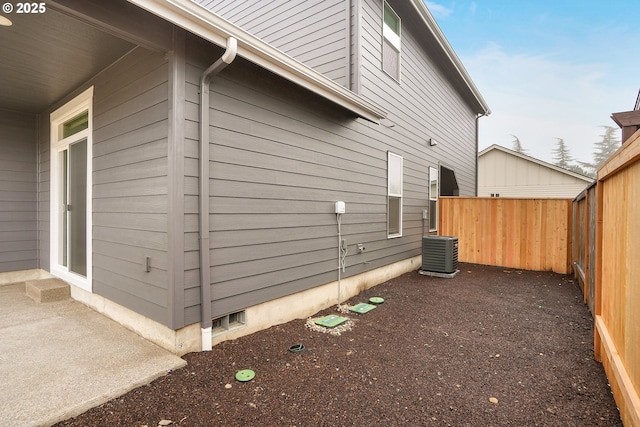 view of home's exterior with a fenced backyard, central AC, and a patio