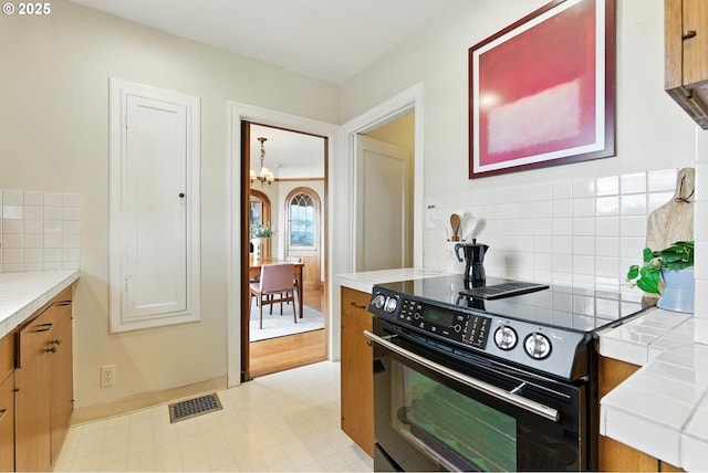 368 NW Lomita Ter, Portland, OR 97210 - kitchen with black electric range oven, a chandelier, tasteful backsplash, tile counters, and light floors