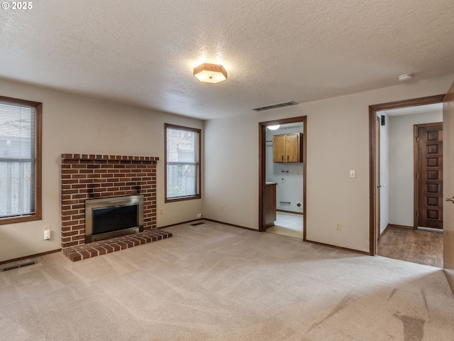 unfurnished living room featuring light colored carpet, a fireplace, and a textured ceiling