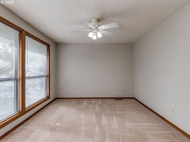 spare room with ceiling fan, light colored carpet, and a textured ceiling