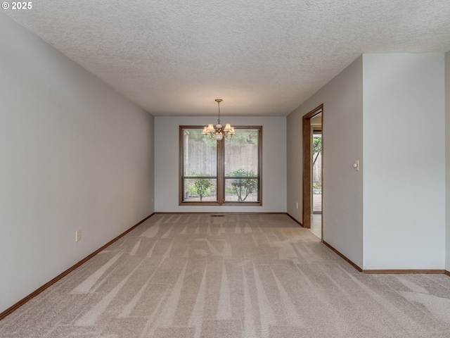 carpeted empty room with a chandelier and a textured ceiling