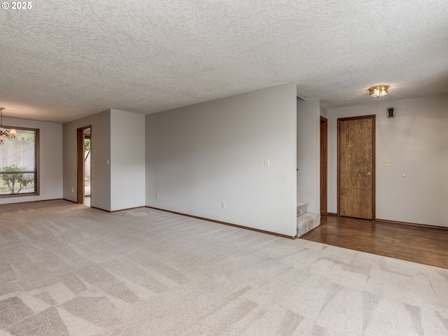 carpeted empty room with a textured ceiling and a chandelier