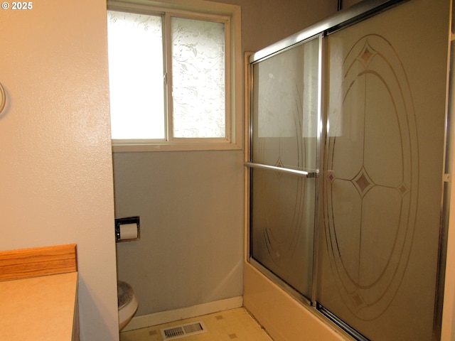 bathroom with visible vents, toilet, enclosed tub / shower combo, vanity, and baseboards