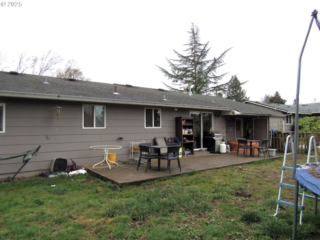 back of property featuring a trampoline, a lawn, and a patio