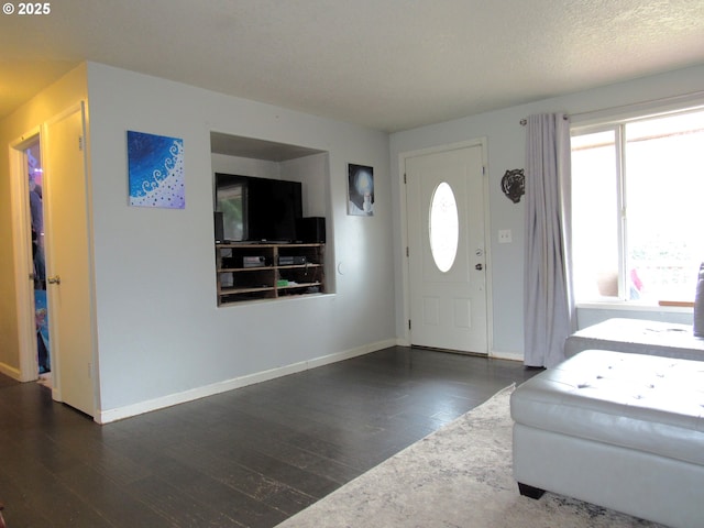 foyer entrance with baseboards, dark wood finished floors, and a textured ceiling