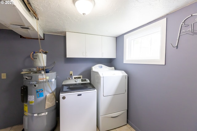 215 W 9th St, The Dalles, OR 97058 - washroom with strapped water heater, separate washer and dryer, cabinet space, and light tile patterned floors