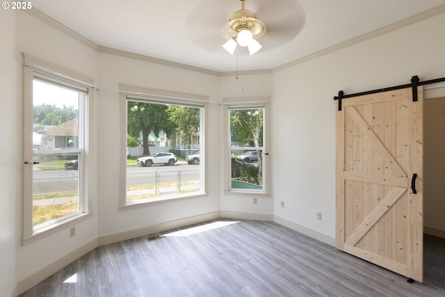 215 W 9th St, The Dalles, OR 97058 - empty room with wood finished floors, a barn door, ceiling fan, and ornamental molding