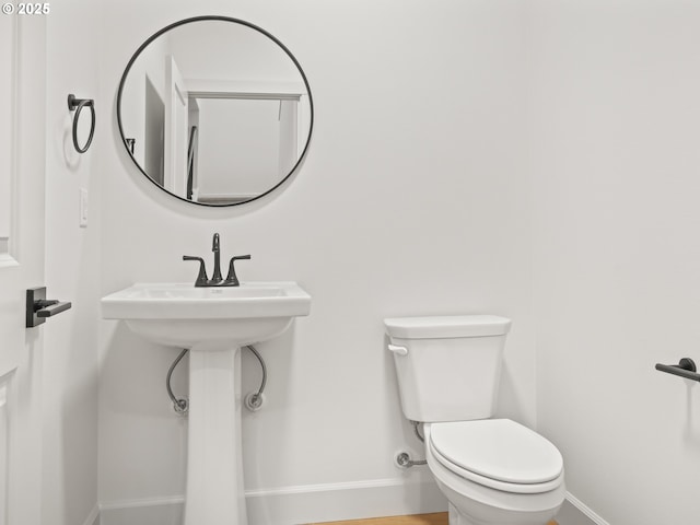 half bath featuring toilet and baseboards