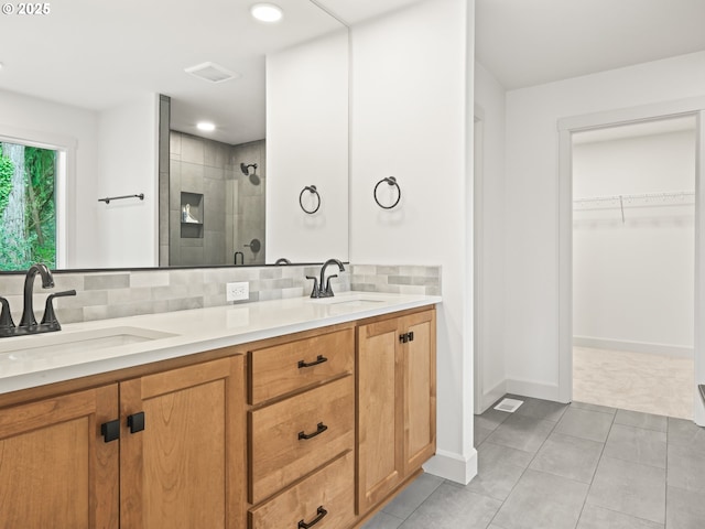 bathroom featuring a sink, decorative backsplash, a spacious closet, and a shower stall