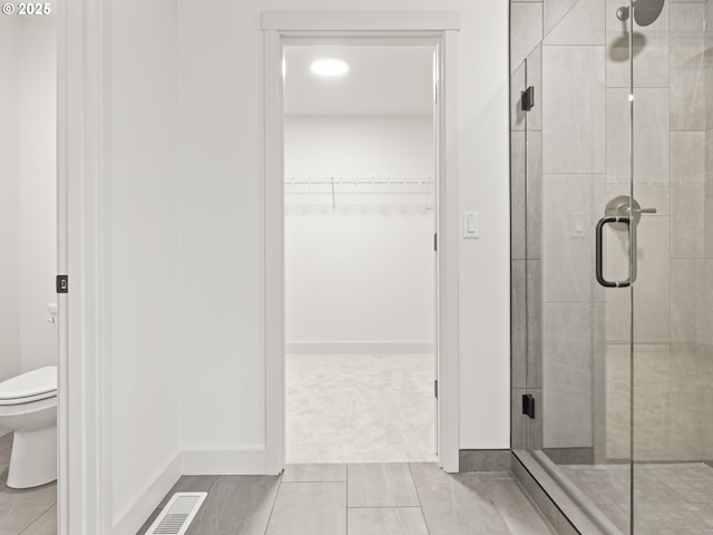 bathroom with visible vents, a stall shower, a spacious closet, tile patterned floors, and toilet