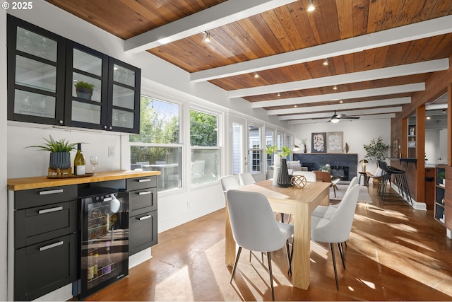 dining area featuring wine cooler, wooden ceiling, a dry bar, a fireplace, and ceiling fan