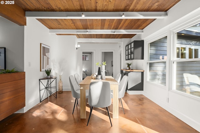 dining area with beam ceiling, concrete flooring, and baseboards