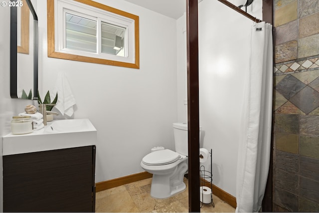 full bathroom featuring stone tile floors, toilet, tiled shower, and baseboards