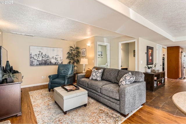 living area featuring visible vents, baseboards, a textured ceiling, and wood finished floors