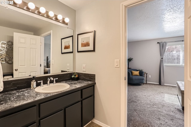 bathroom with a textured ceiling, vanity, and baseboards