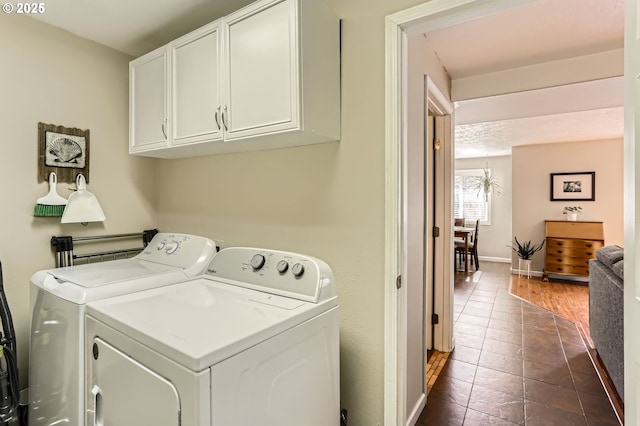 laundry room with cabinet space, washing machine and dryer, baseboards, and dark tile patterned floors