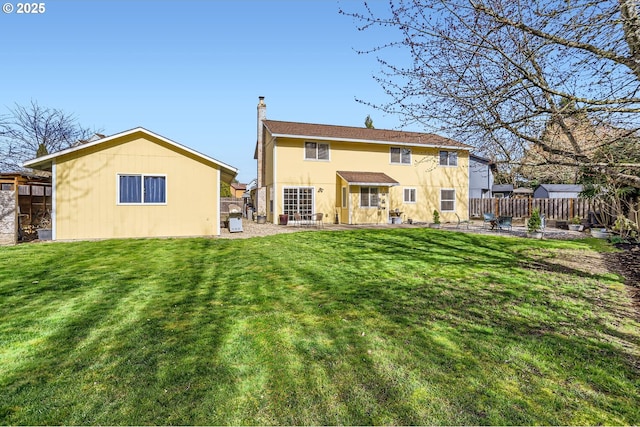 back of property featuring a yard, a chimney, a patio area, and fence