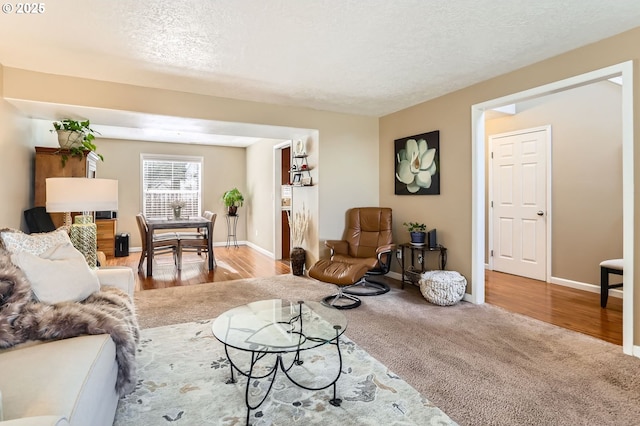 living room with a textured ceiling, baseboards, and wood finished floors