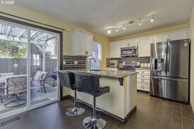4422 SW Appletree Pl, Beaverton, OR 97078 - kitchen with stainless steel appliances, light stone counters, a peninsula, white cabinets, and decorative backsplash